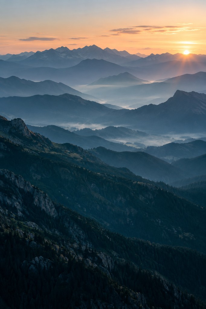 Layered alpine ridges in blue dawn haze